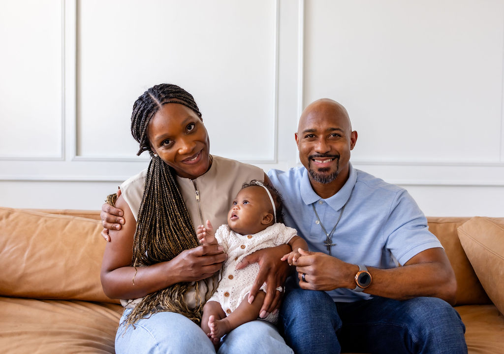 Parents holding their infant together on a sofa