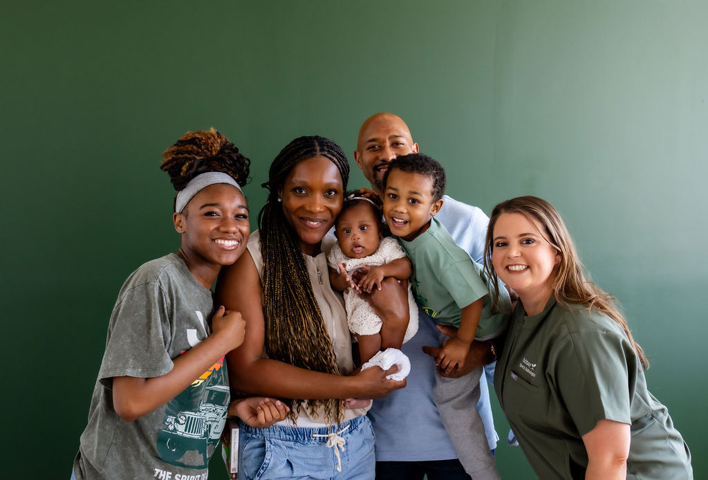 A family with parents, an infant, and older children posing with Brittany Shockley