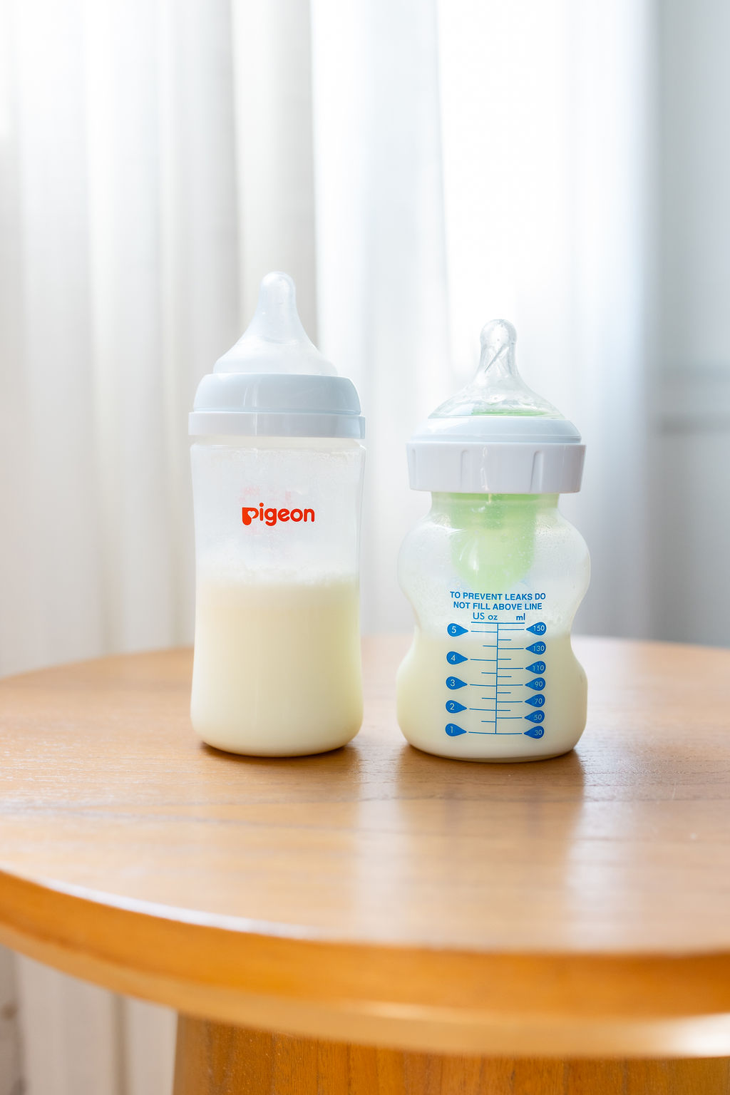 Two baby bottles containing milk on a wooden table