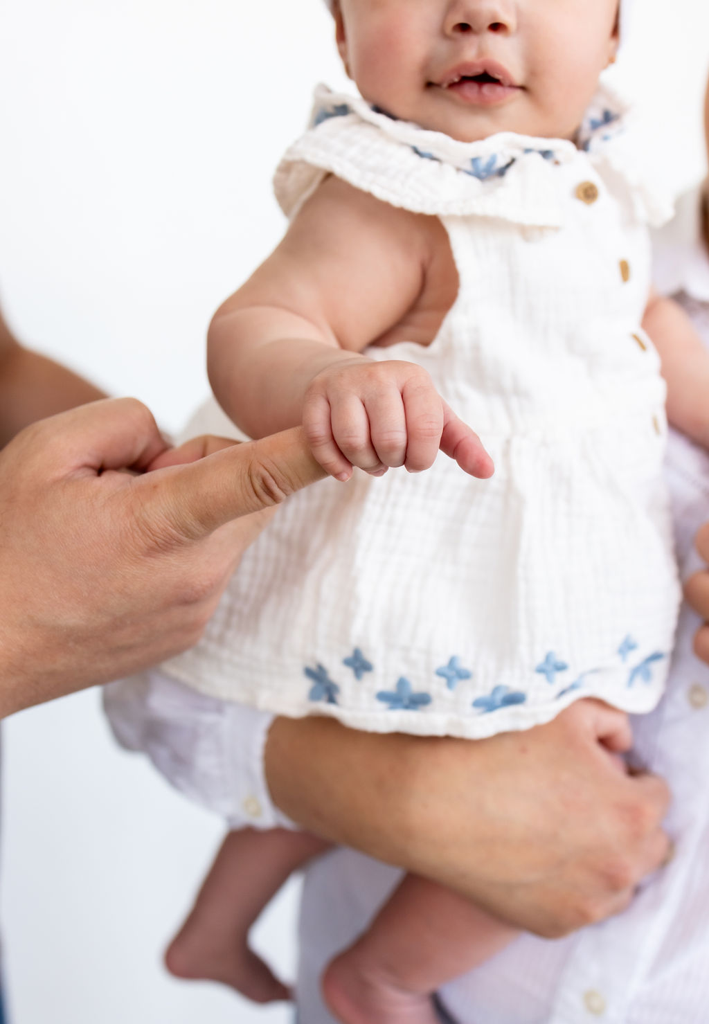 An infant grasping a caregiver's finger